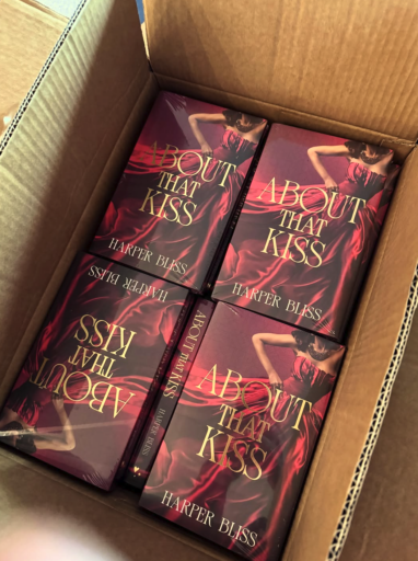 Several copies of the About That Kiss Deluxe Edition packed in a cardboard shipping box